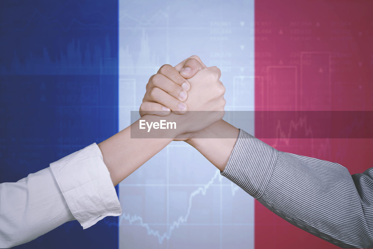 Cropped image of business people holding hands against french flag