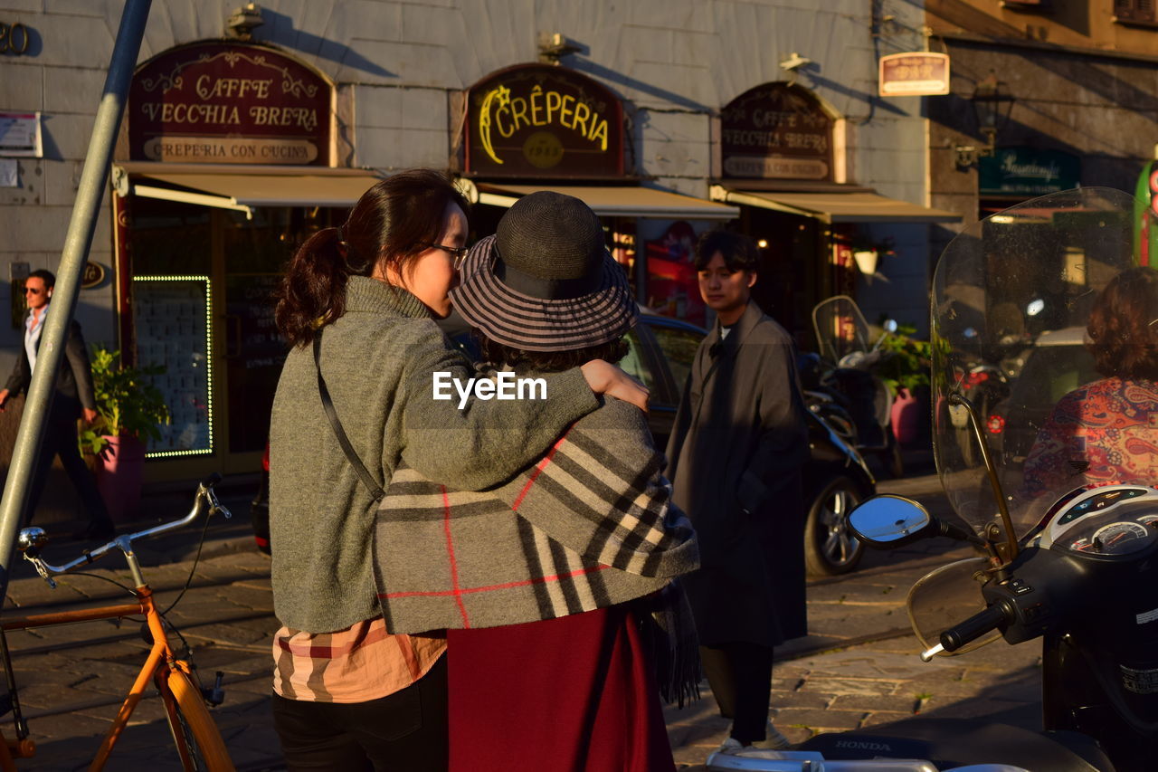 REAR VIEW OF PEOPLE WALKING ON STREET MARKET