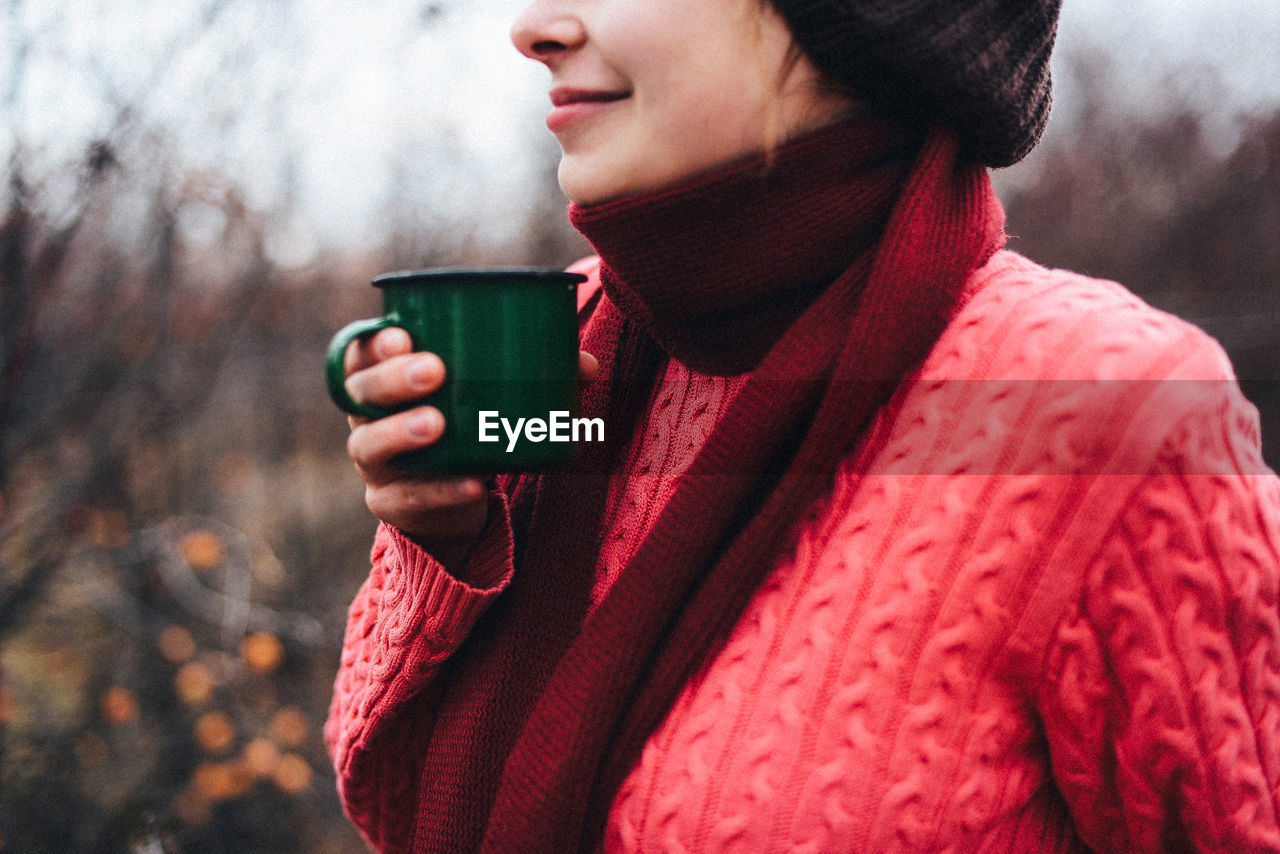 Midsection of woman holding coffee cup outdoors