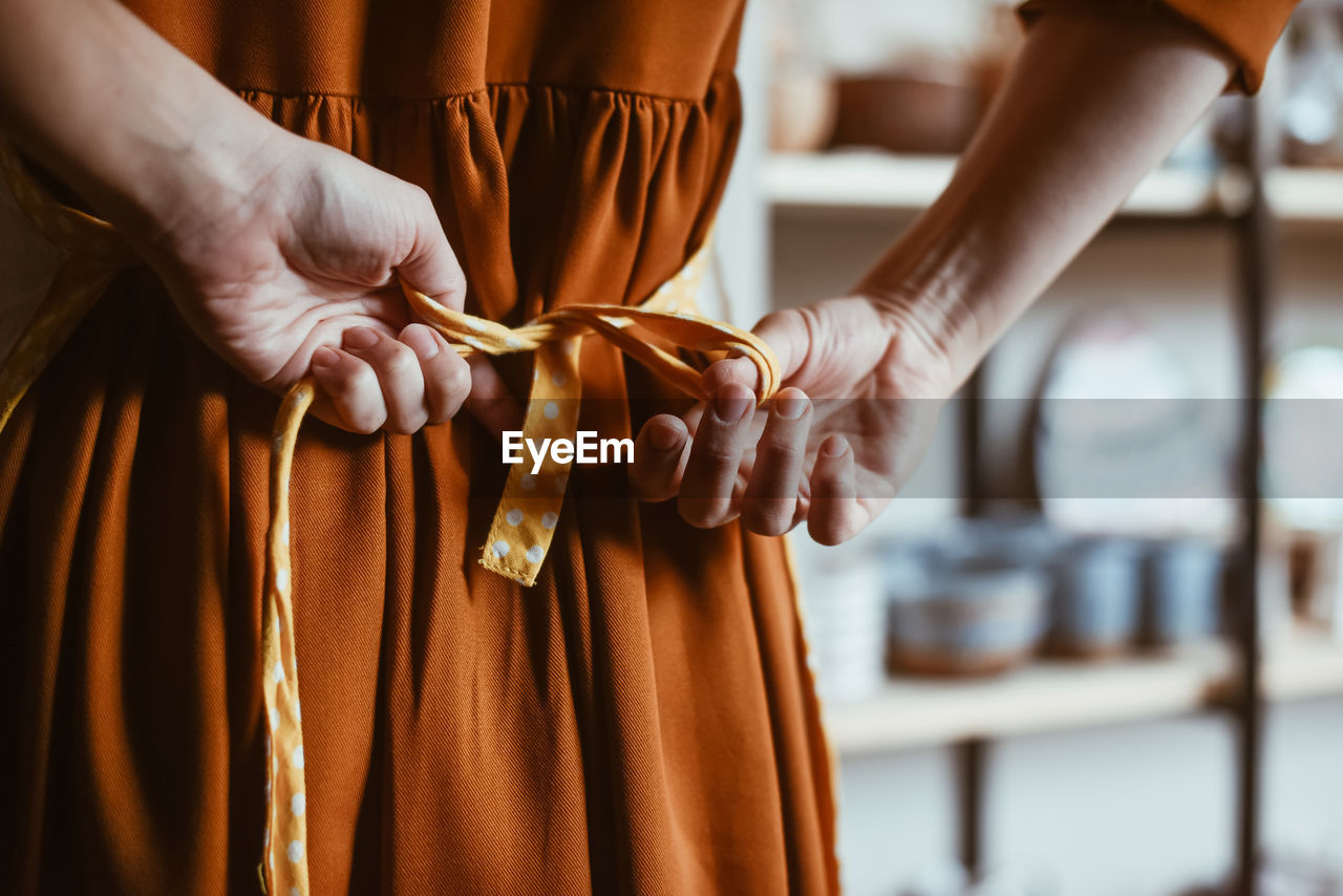 Potter woman getting ready for work by putting on apron person