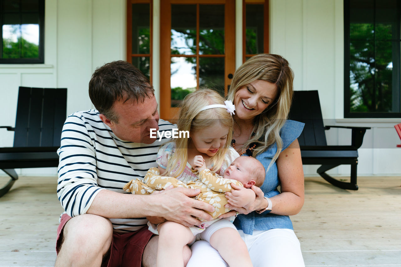 A new family sitting together on a modern farmhouse porch