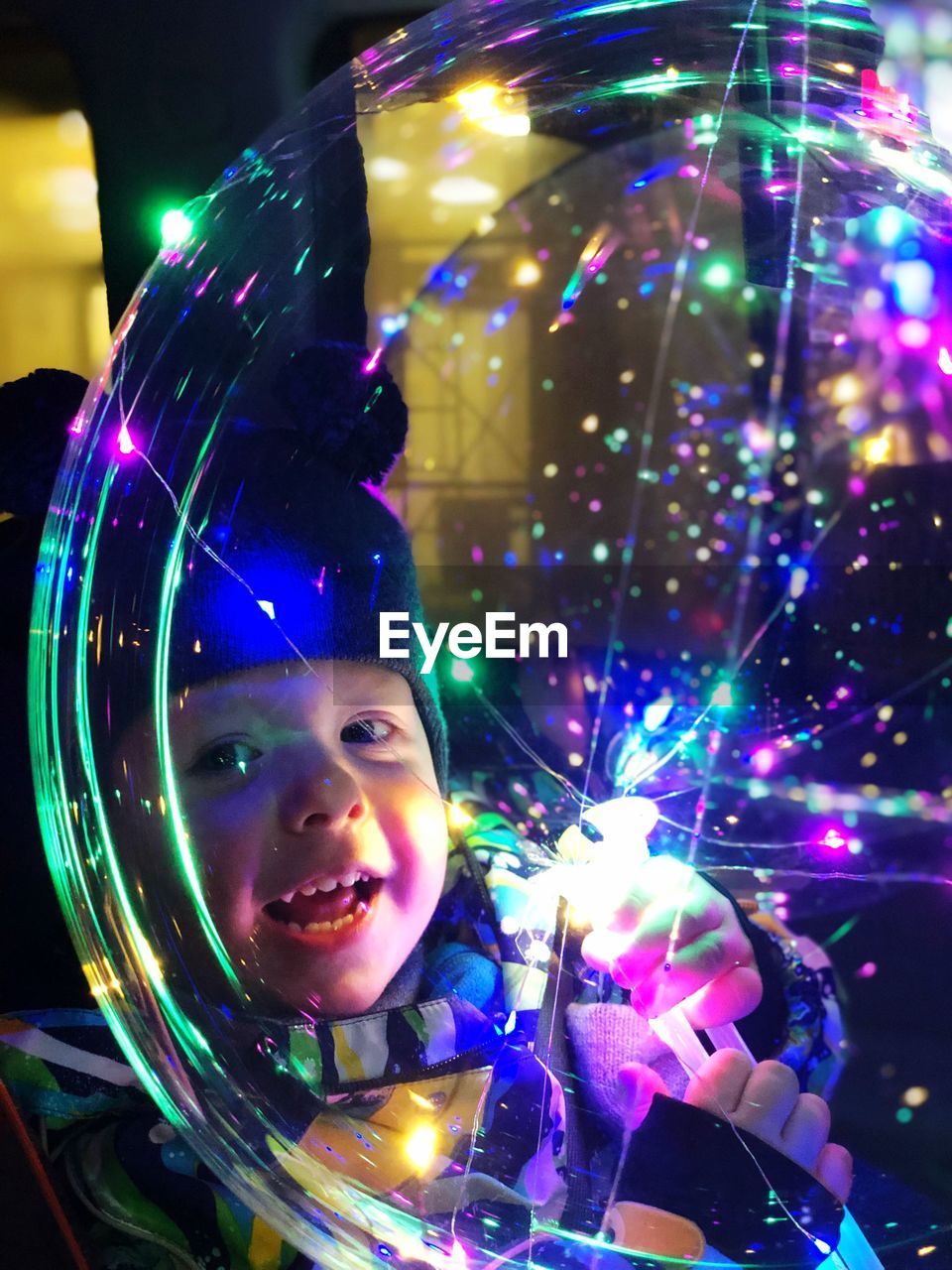 PORTRAIT OF SMILING GIRL WITH ILLUMINATED LIGHTS