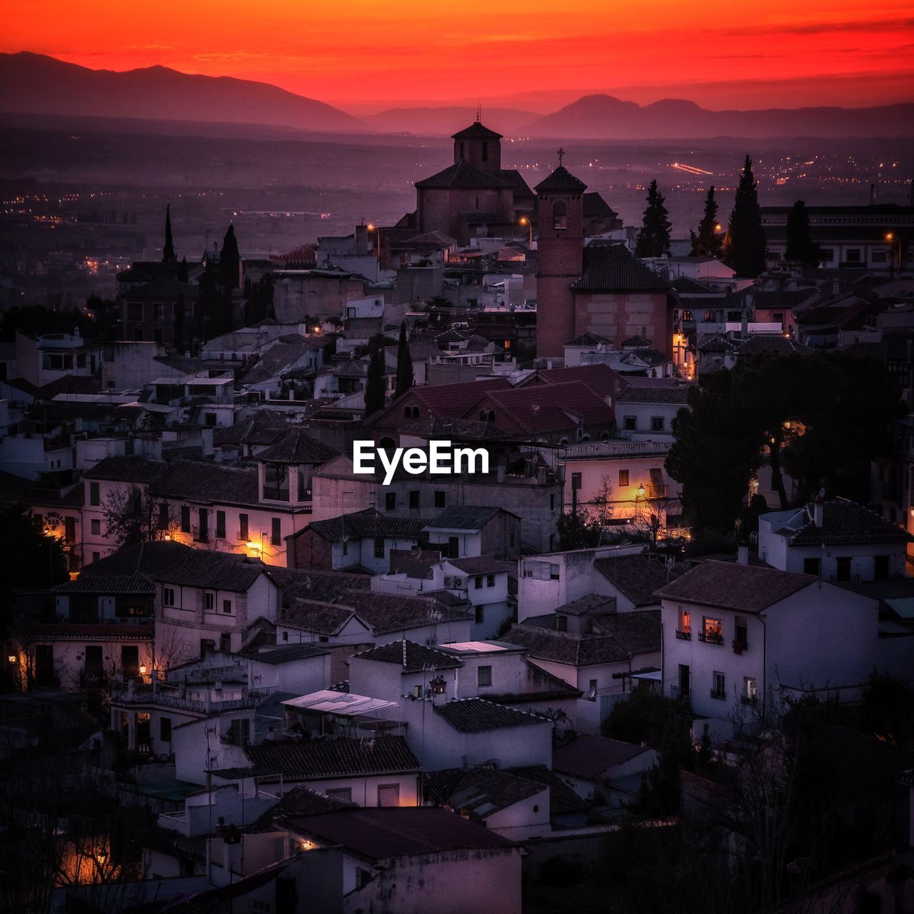 Aerial view of illuminated buildings in city against sky during sunset