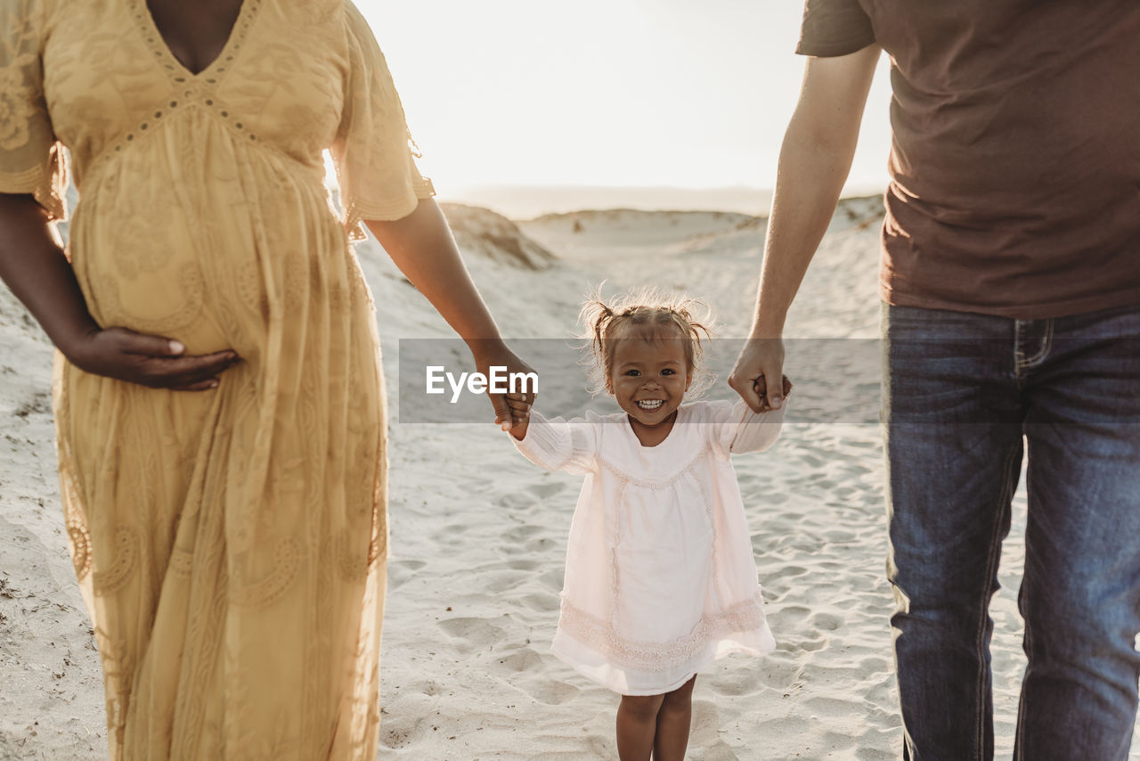 Young family of three walking and playing at beach