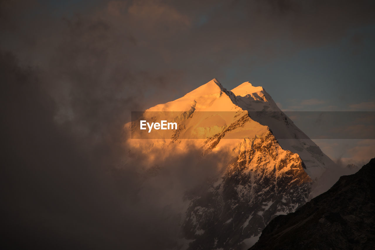 LOW ANGLE VIEW OF SNOWCAPPED MOUNTAINS AGAINST SKY AT SUNSET