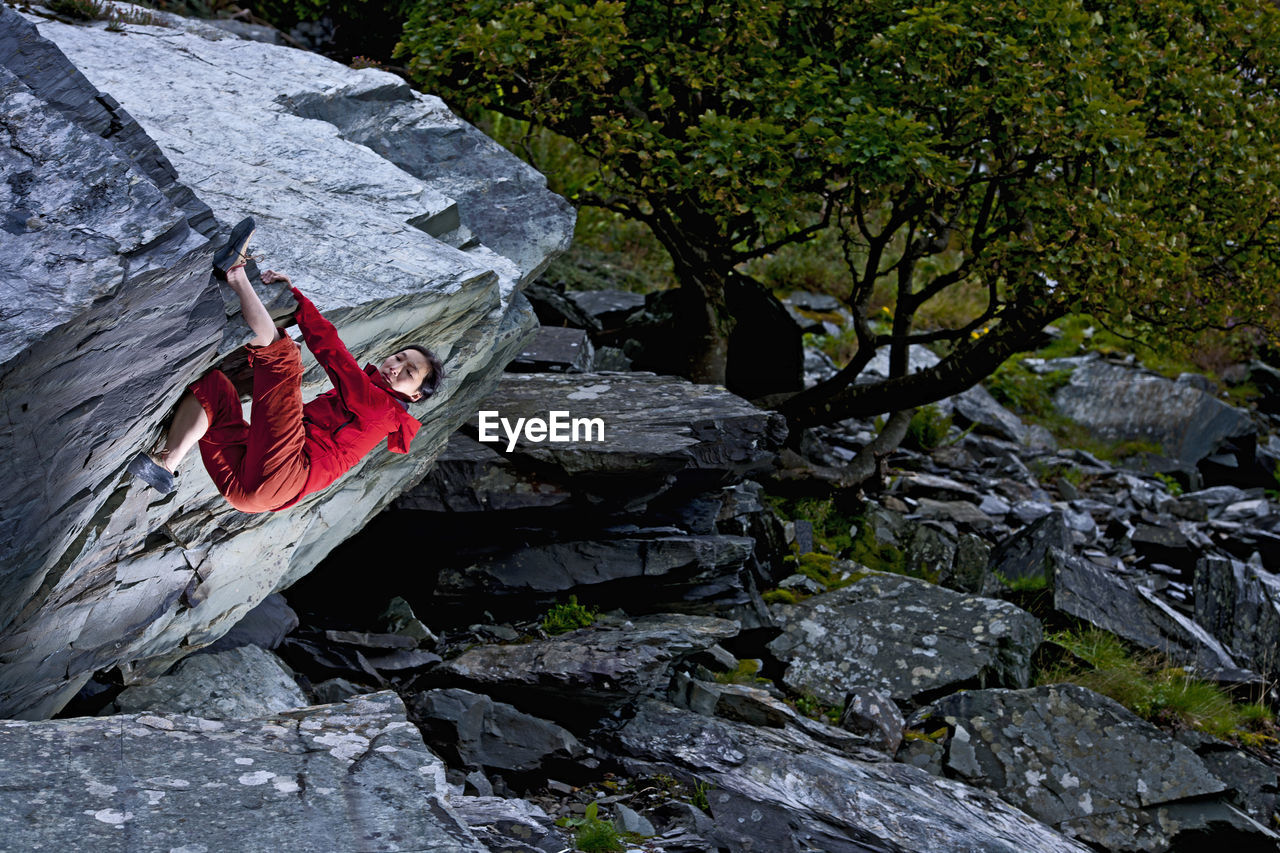 Woman bouldering on rock at slate quarry in north wales