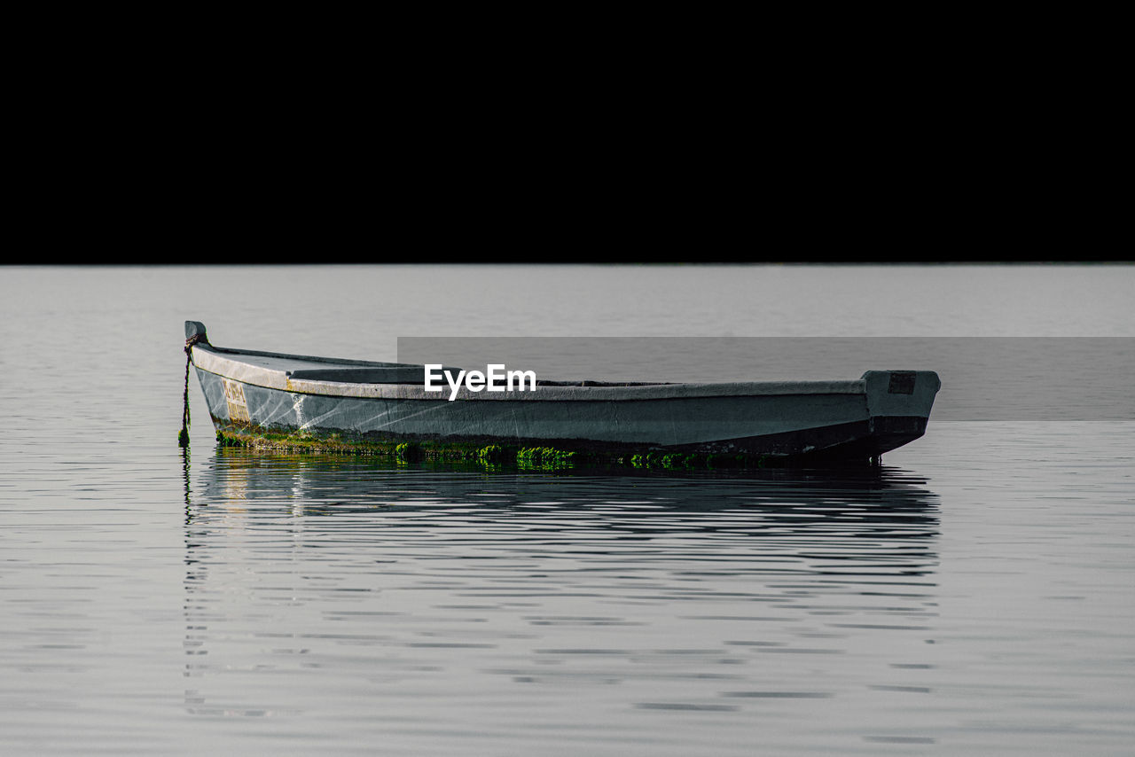 BOAT MOORED IN LAKE AGAINST SKY
