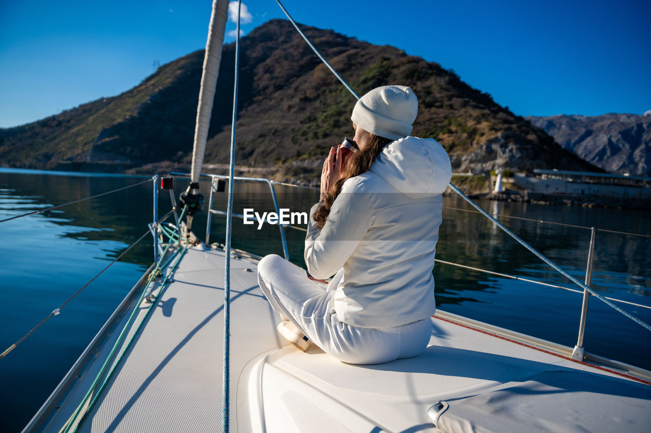 rear view of woman standing by sea against clear sky