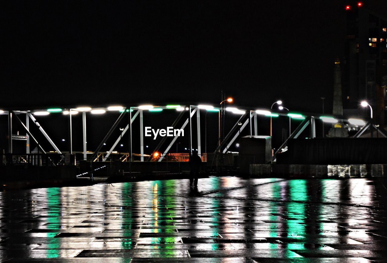 Illuminated bridge over river against sky at night