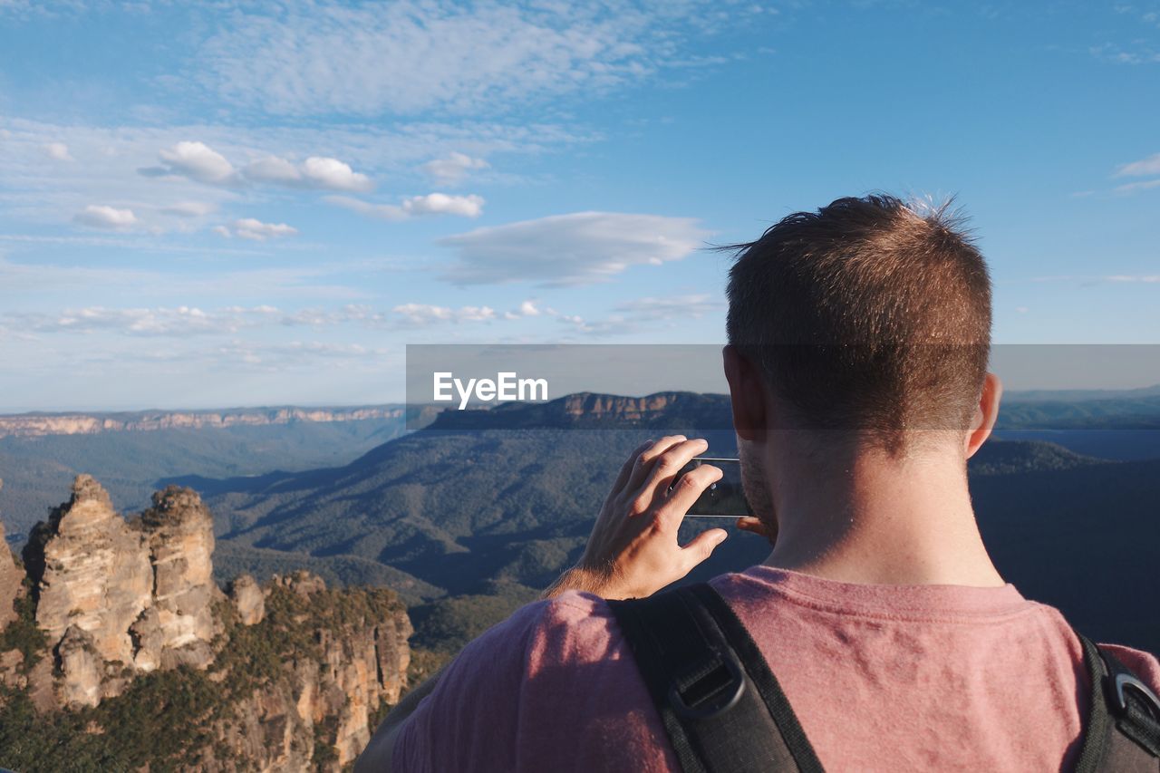 Rear view of man photographing mountain through camera