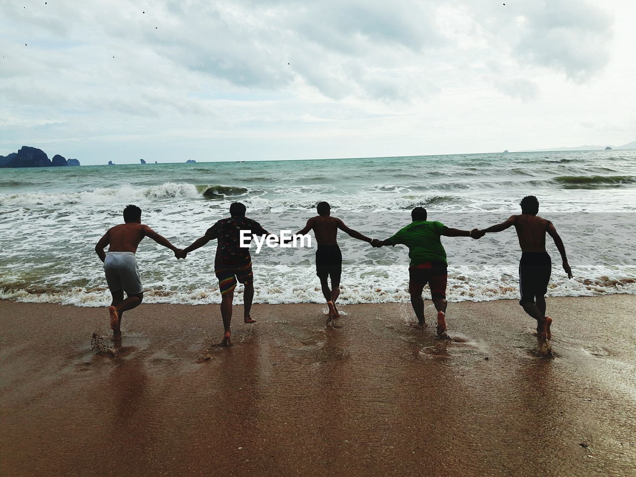 People running at beach against sky