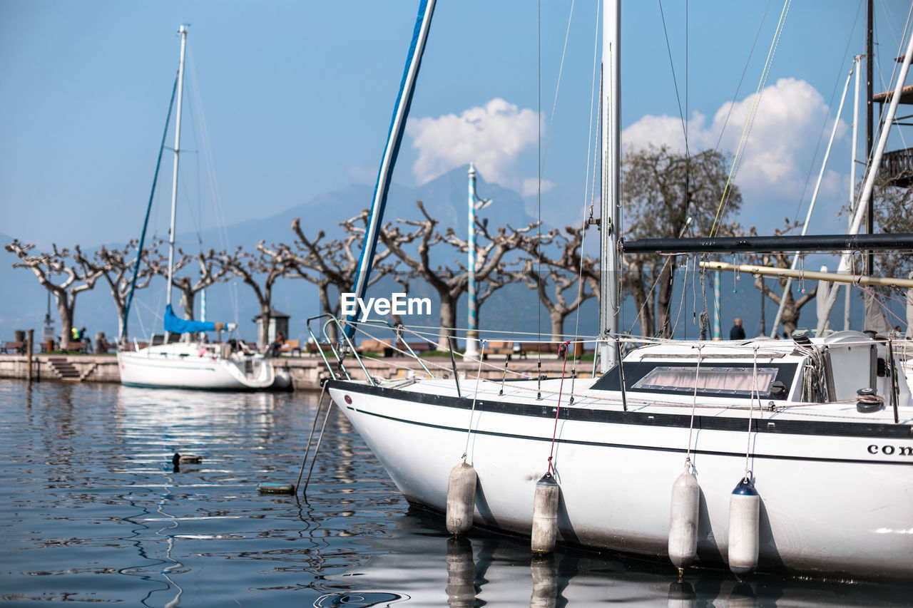 Sailboats moored on sea against sky