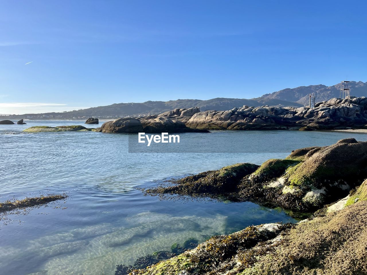 water, body of water, shore, sea, scenics - nature, sky, coast, beauty in nature, nature, ocean, landscape, land, mountain, environment, bay, rock, tranquility, no people, tranquil scene, beach, clear sky, reflection, travel destinations, day, blue, travel, reservoir, wave, cove, non-urban scene, outdoors, cloud, horizon, sunny, idyllic, wilderness, coastline, sunlight, tourism, mountain range, terrain