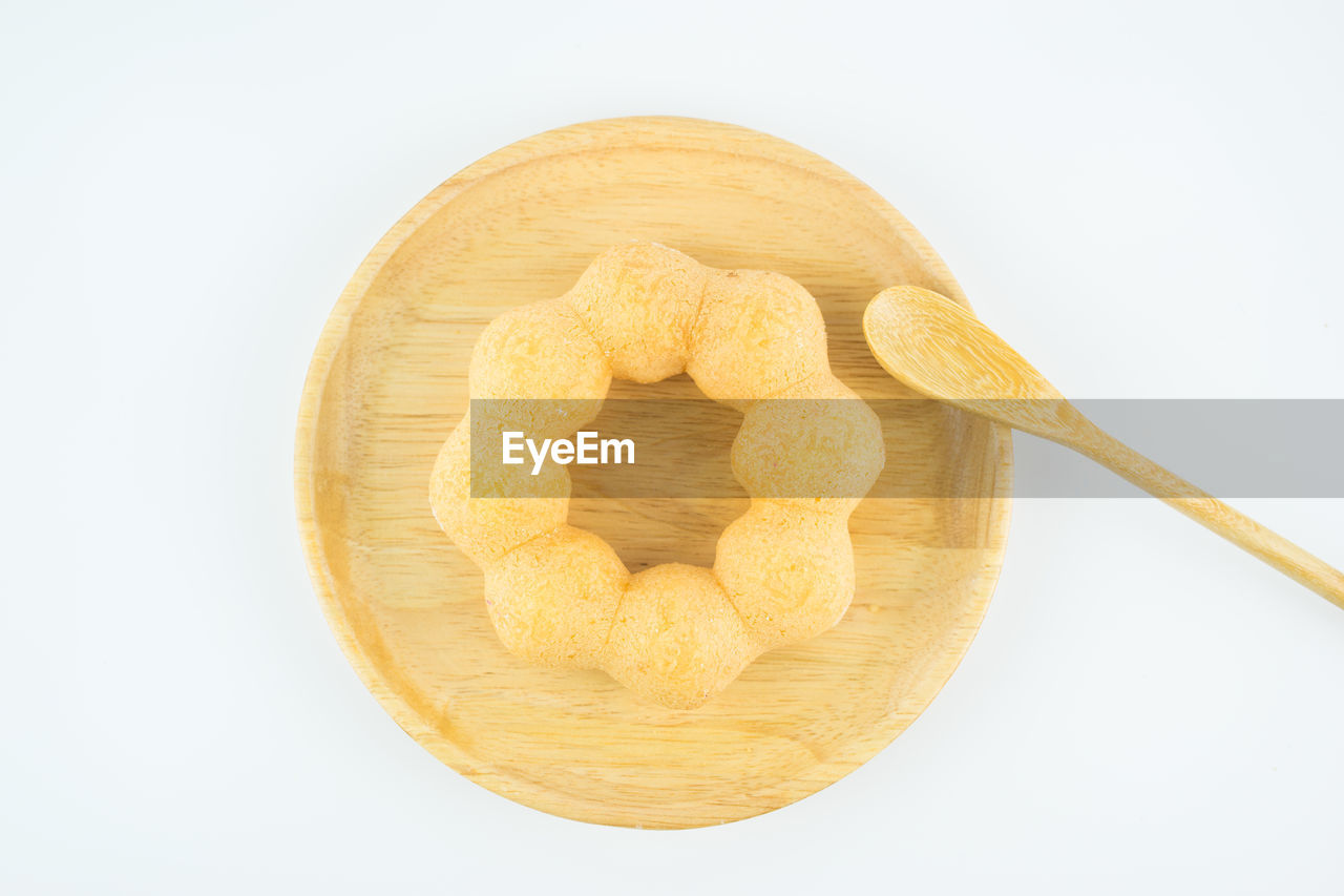 Close-up of food in wooden plate against white background