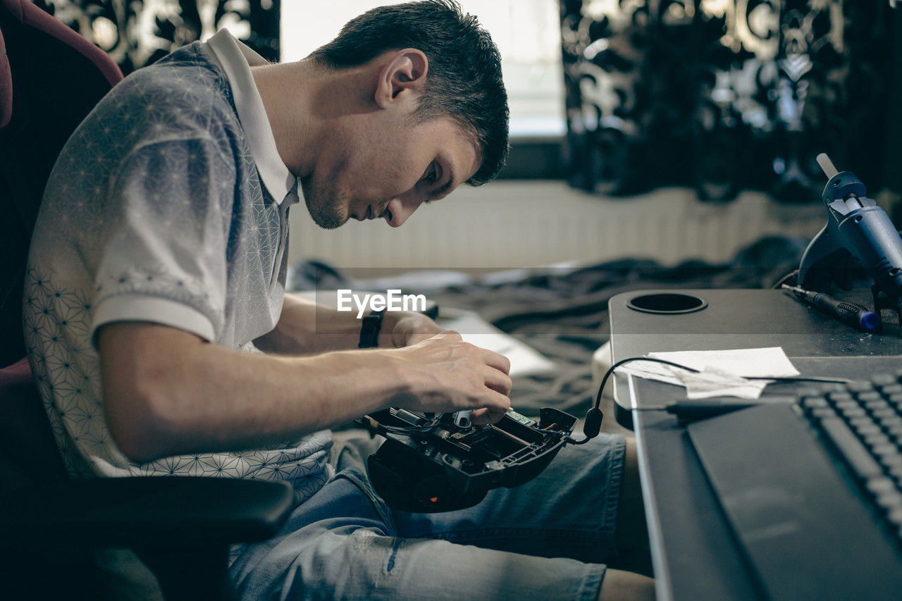 A young man repairs the engine steering wheel on a joystick.