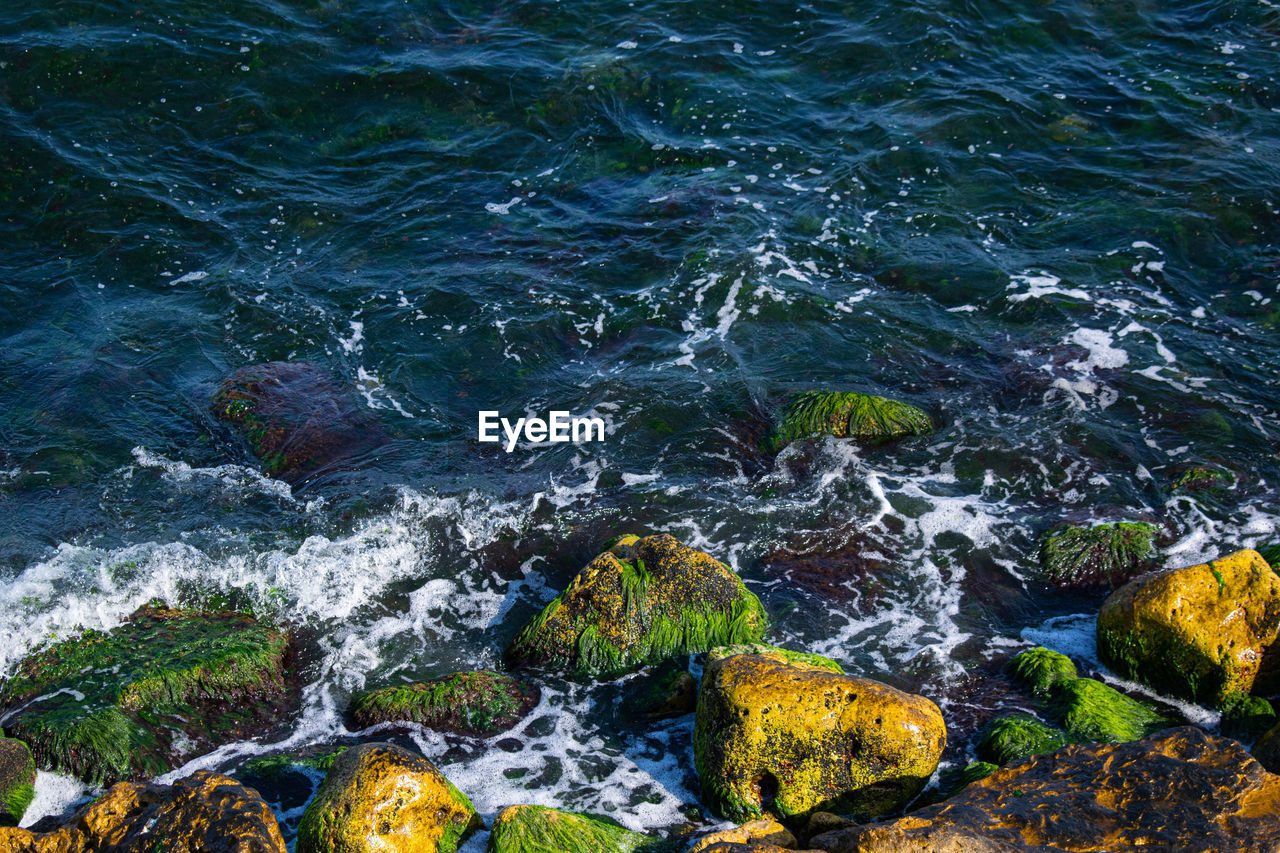 High angle view of sea water flowing through rocks