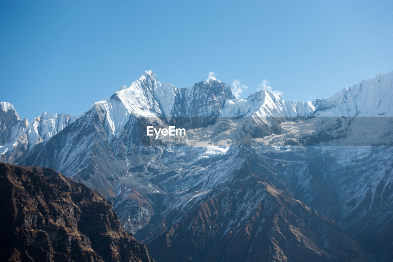 Scenic view of snowcapped mountains against clear blue sky