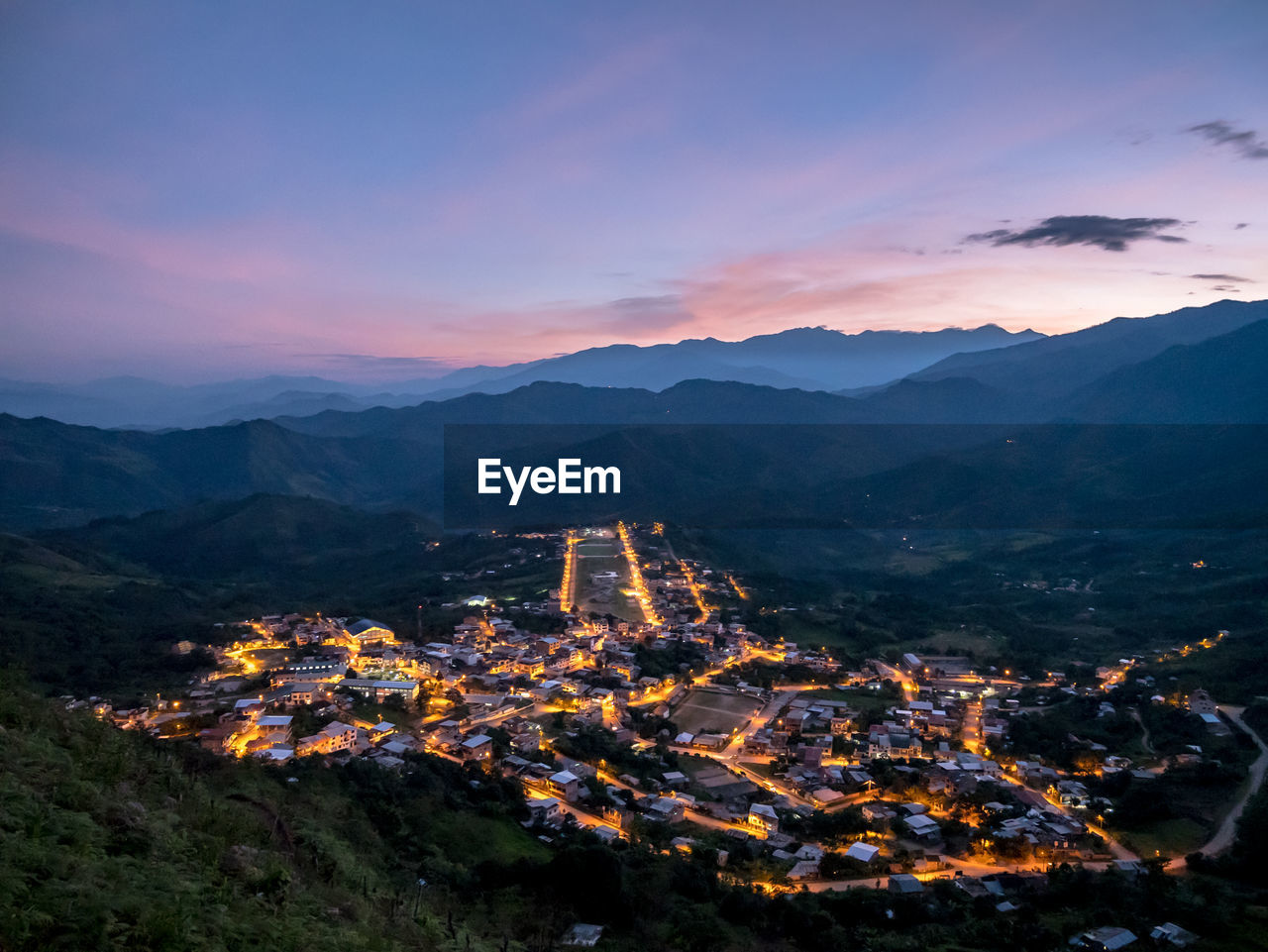 Aerial view of illuminated buildings against sky at sunset