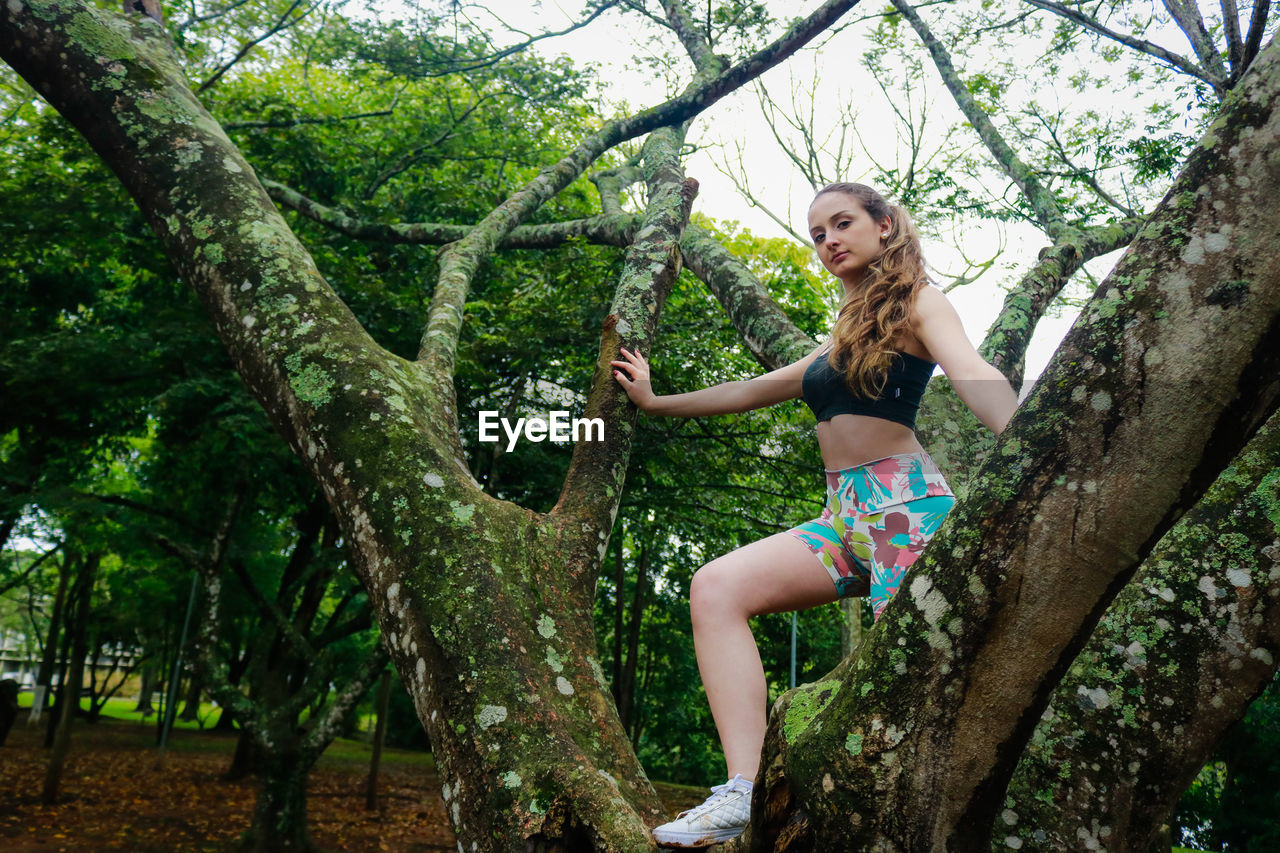 Low angle view of young woman on tree