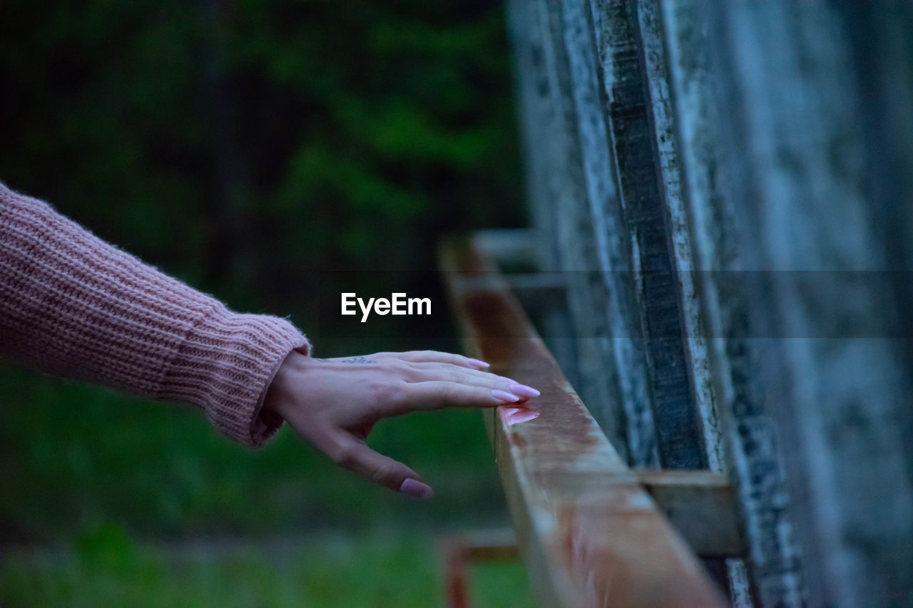 CLOSE-UP OF PERSON HAND TOUCHING FENCE