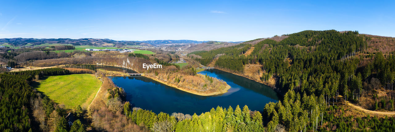 PANORAMIC VIEW OF TREES AND MOUNTAINS AGAINST BLUE SKY