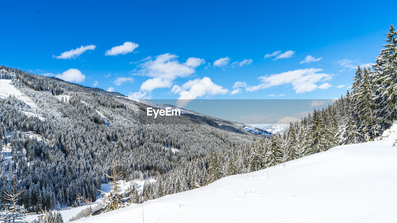 Snow covered landscape against blue sky