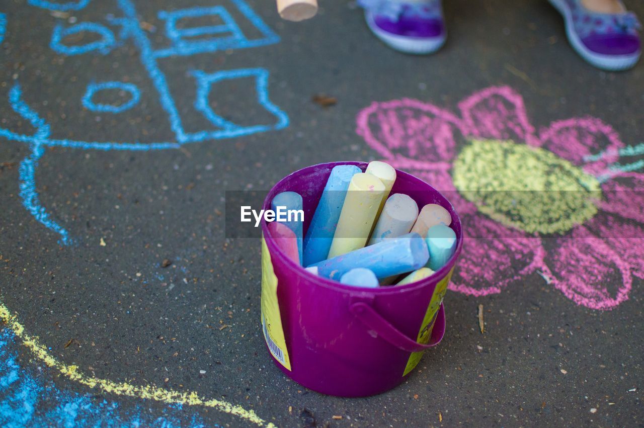 Close-up of container of colorful chalk near chalk drawing