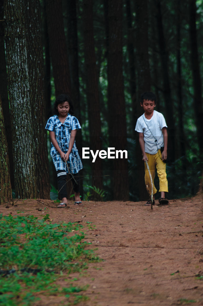 FULL LENGTH OF YOUNG MAN STANDING ON LAND IN FOREST