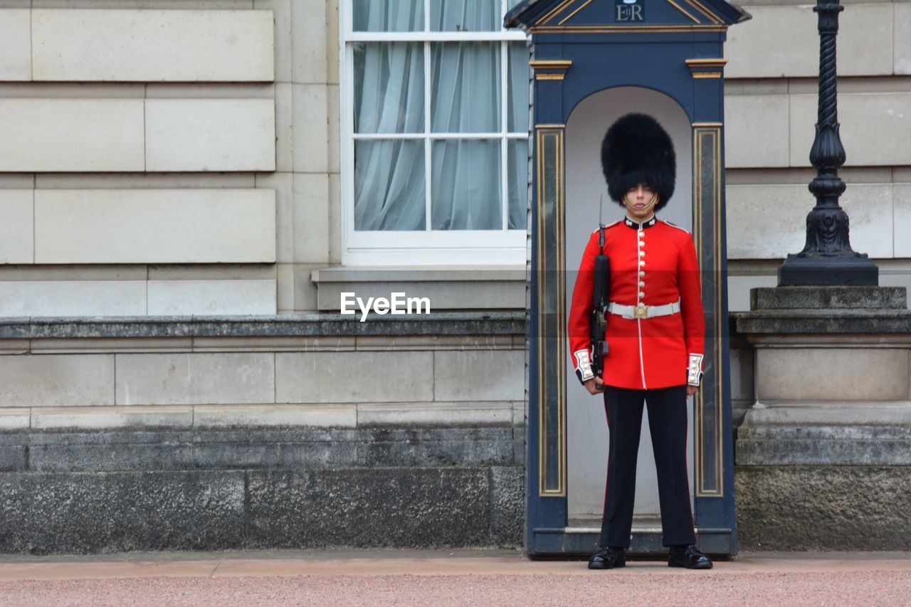 BOY STANDING BY RED DOOR