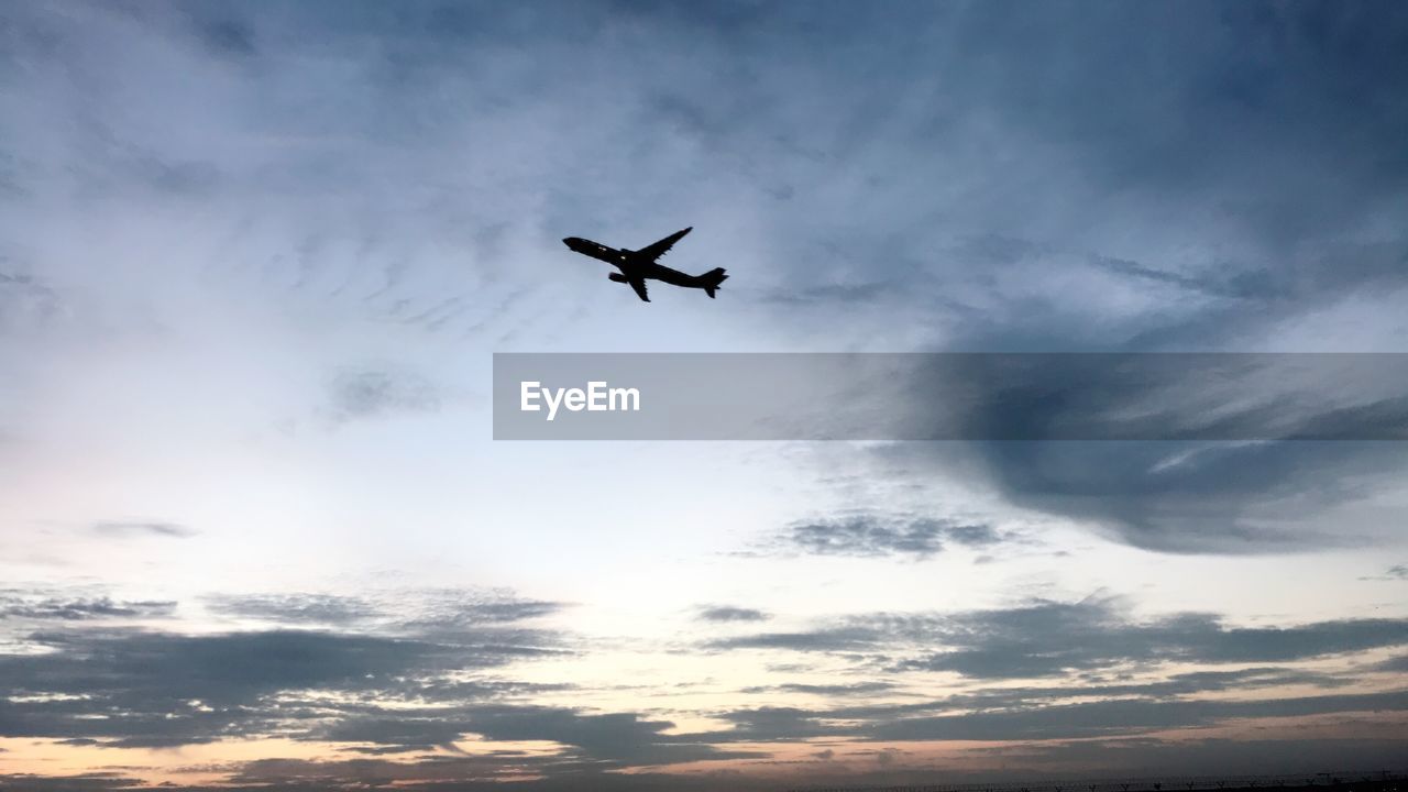 Low angle view of silhouette airplane flying in sky