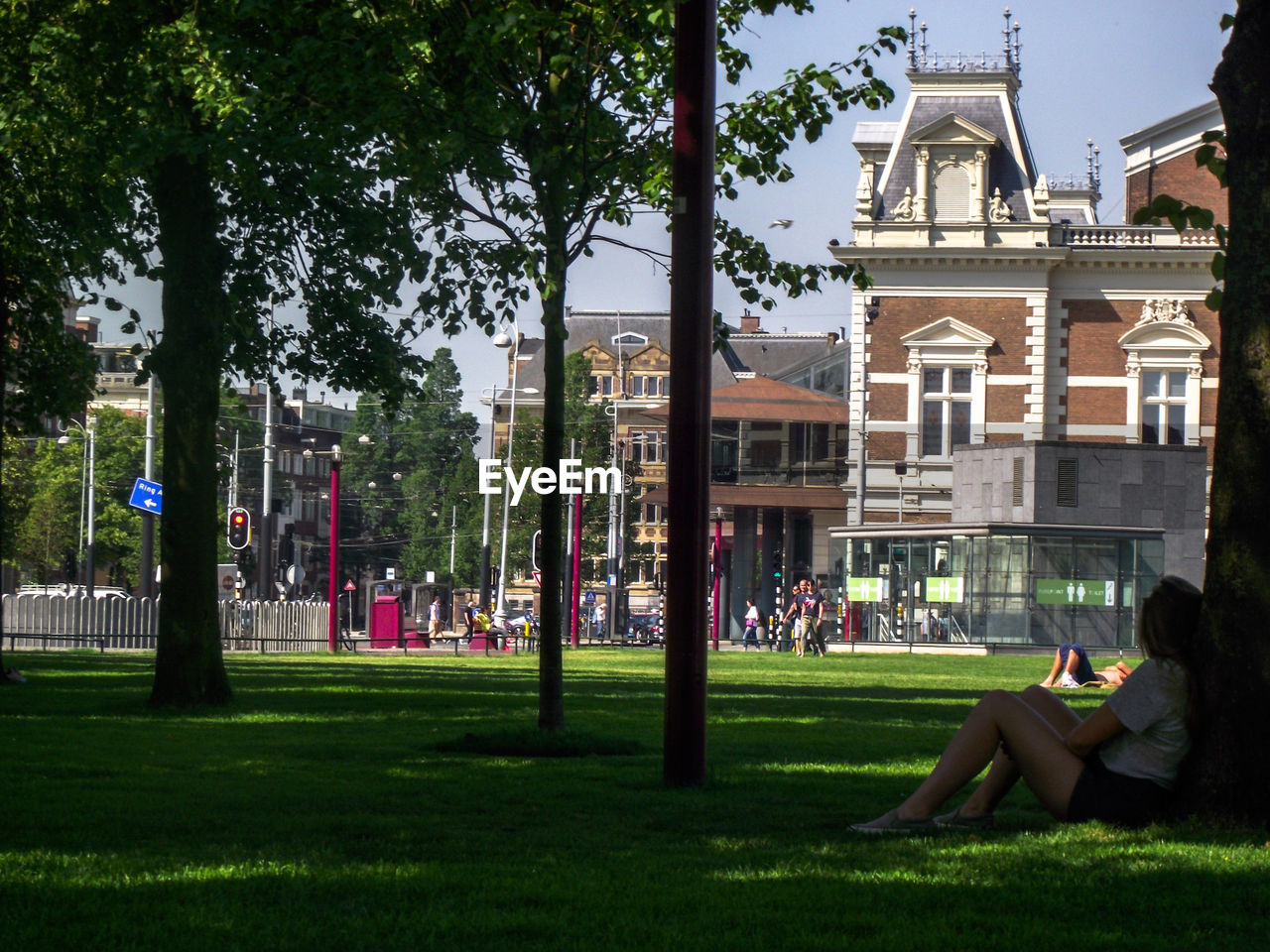 Side view of mid adult woman relaxing on grassy field in park