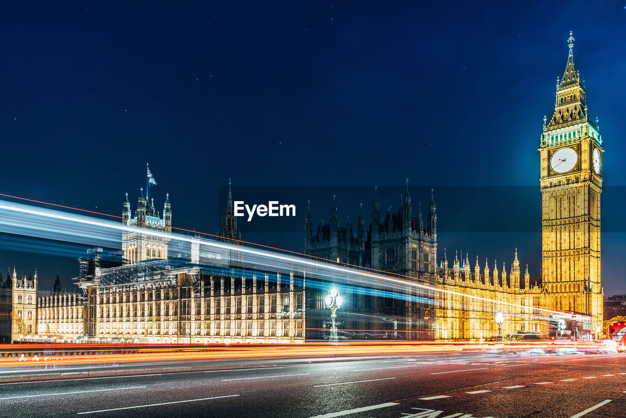 Light trails on road against houses of parliament and big ben