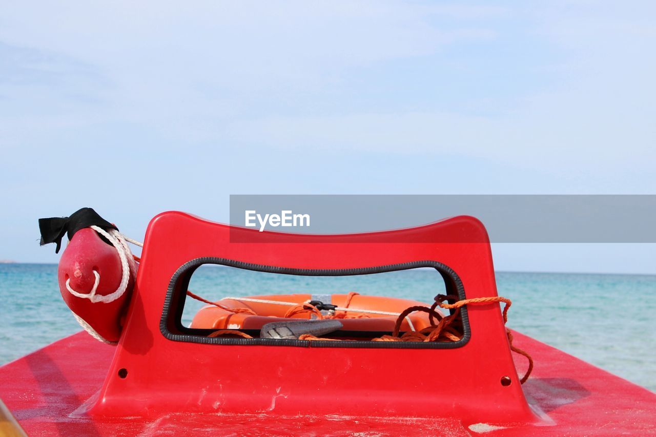 Red lifeboat at sea against sky