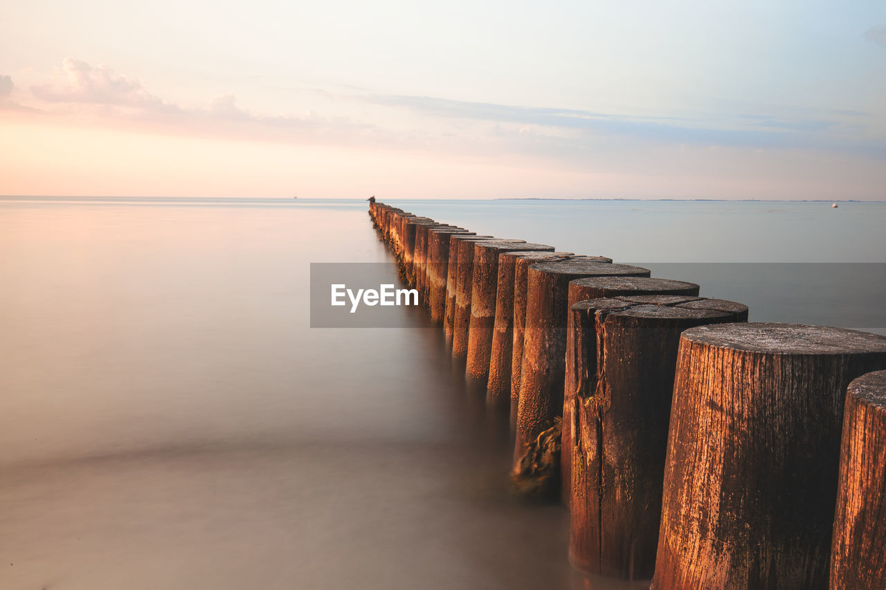 Pier over sea against sky during sunset