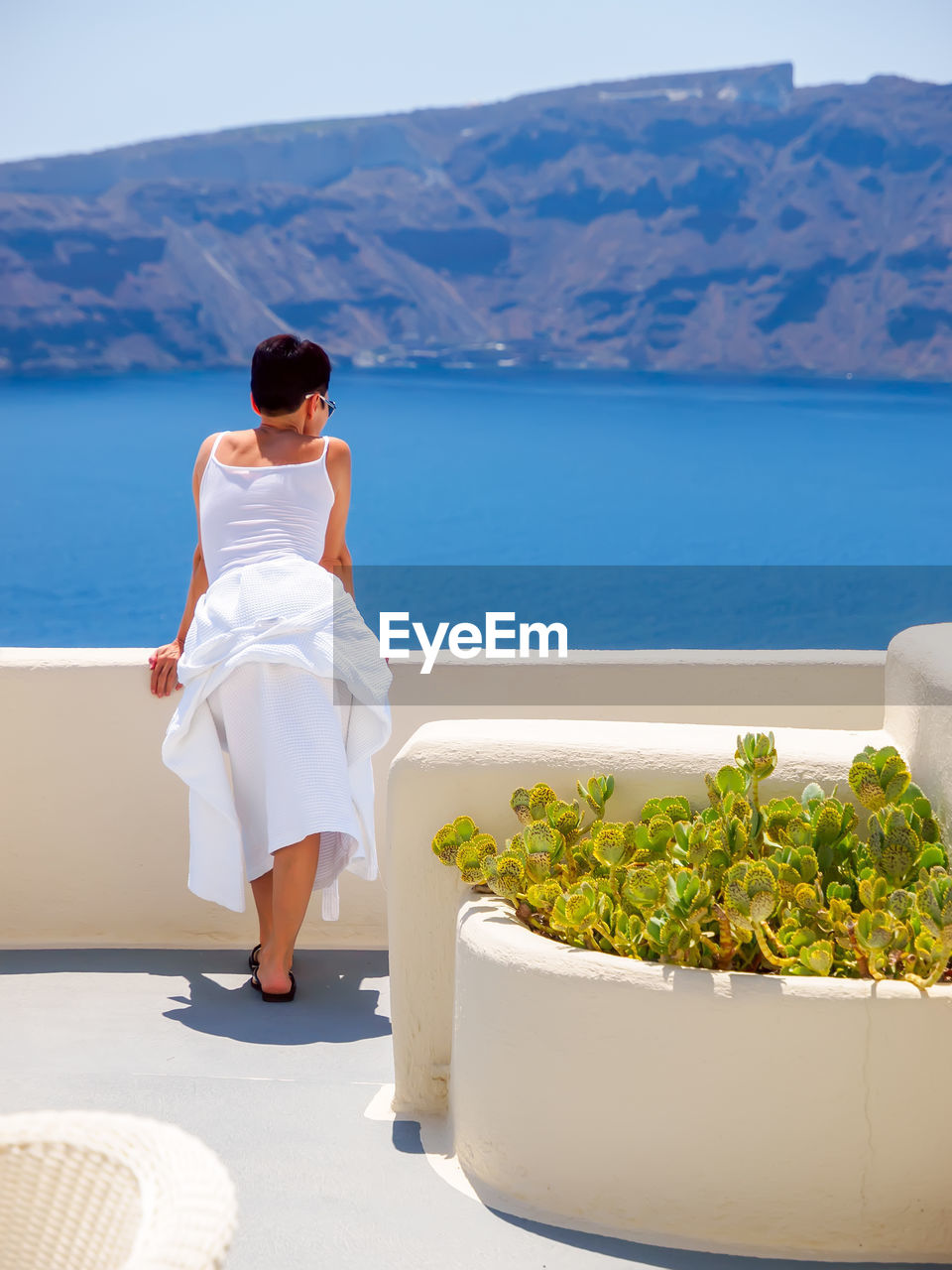 Woman looking and enjoyed on amazing sea view on santorini island from terrace. santorini, greece.