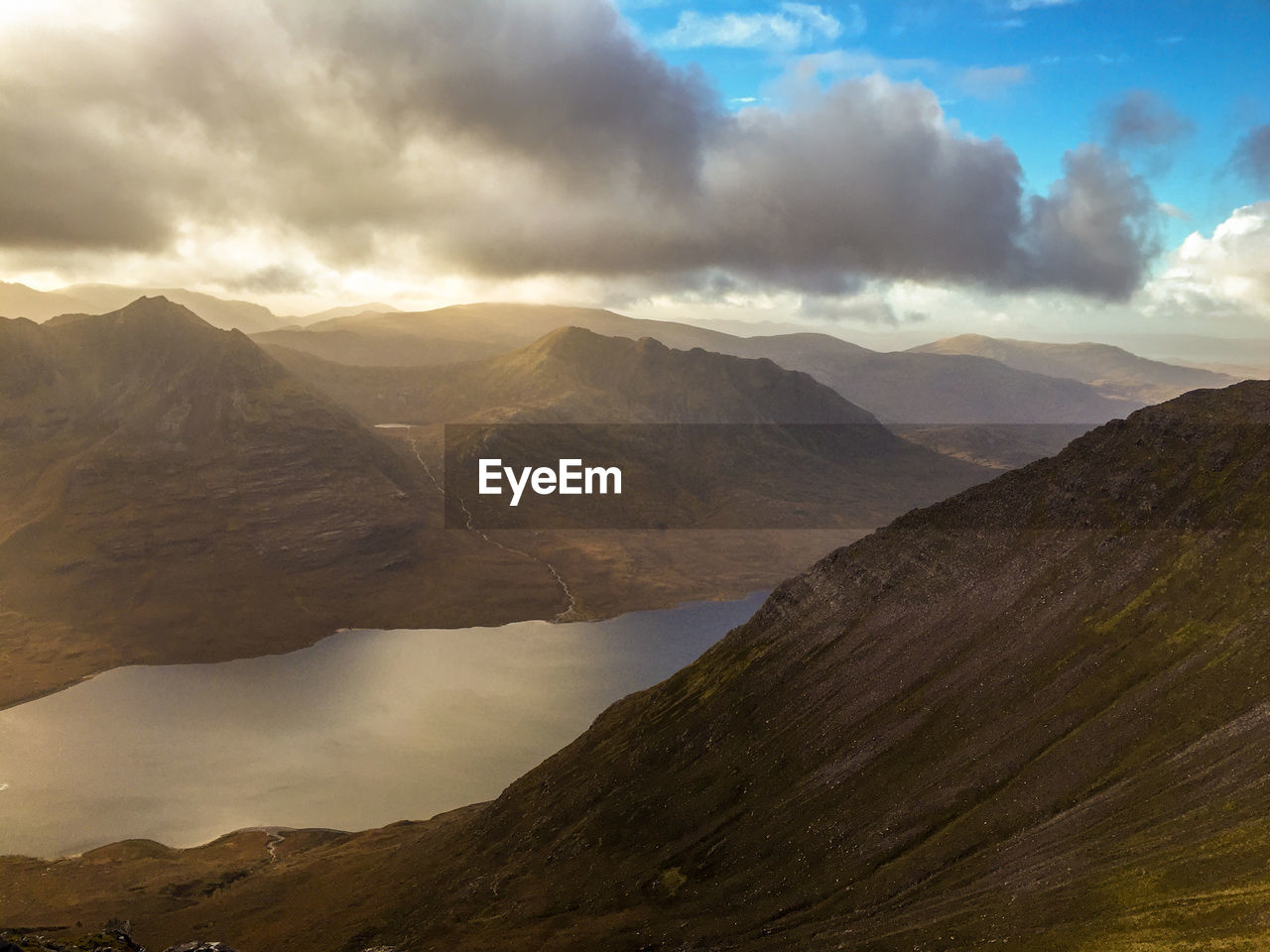 Scenic view of scottish mountains and loch against a cloudy sky. 
