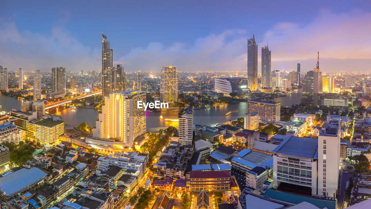 ILLUMINATED MODERN BUILDINGS IN CITY AGAINST SKY DURING SUNRISE