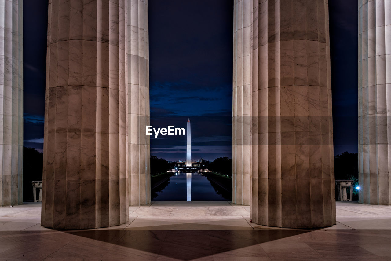 Historical building against sky at night seen through columns