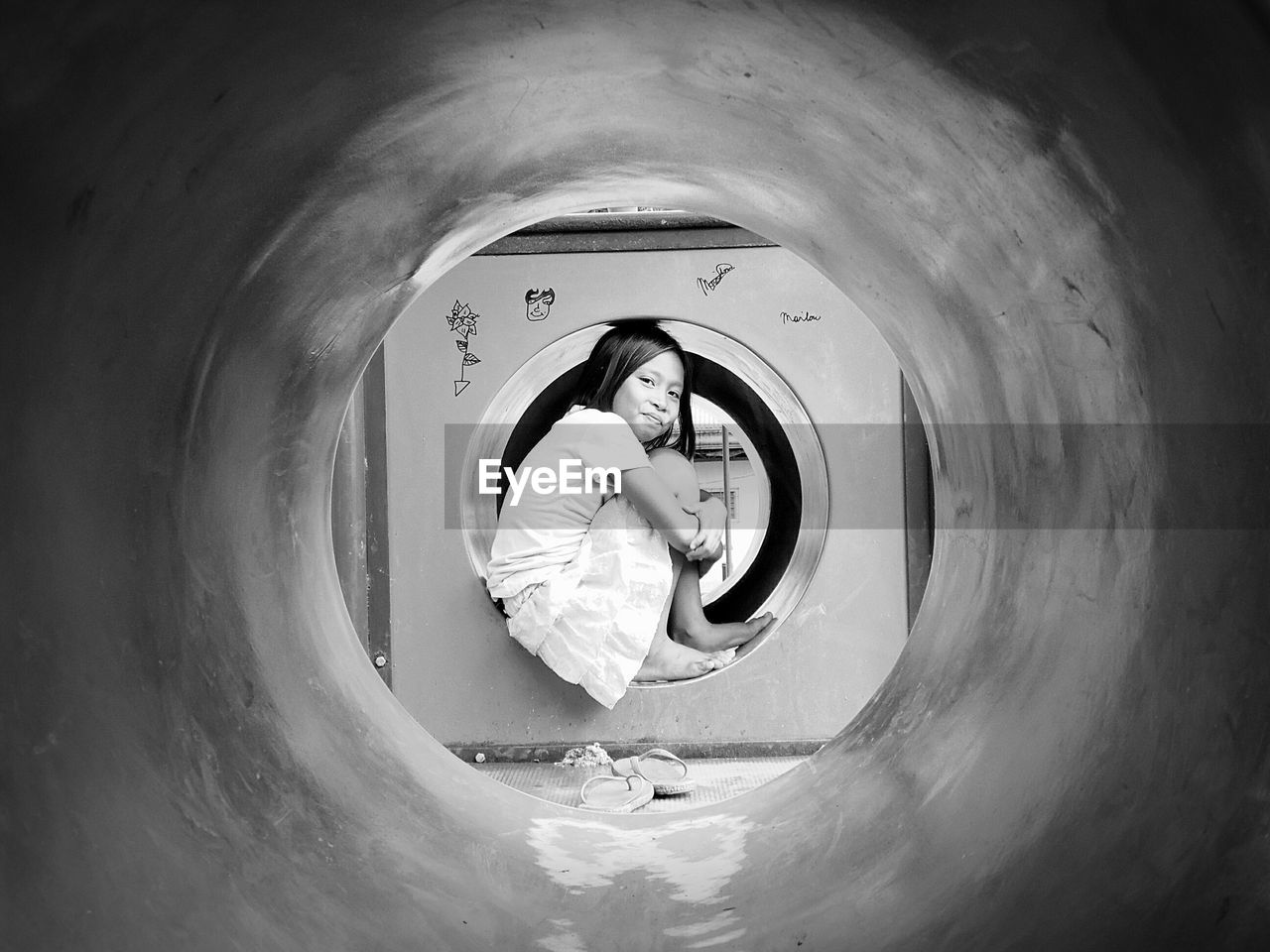 Portrait of girl playing in jungle gym seen from pipe