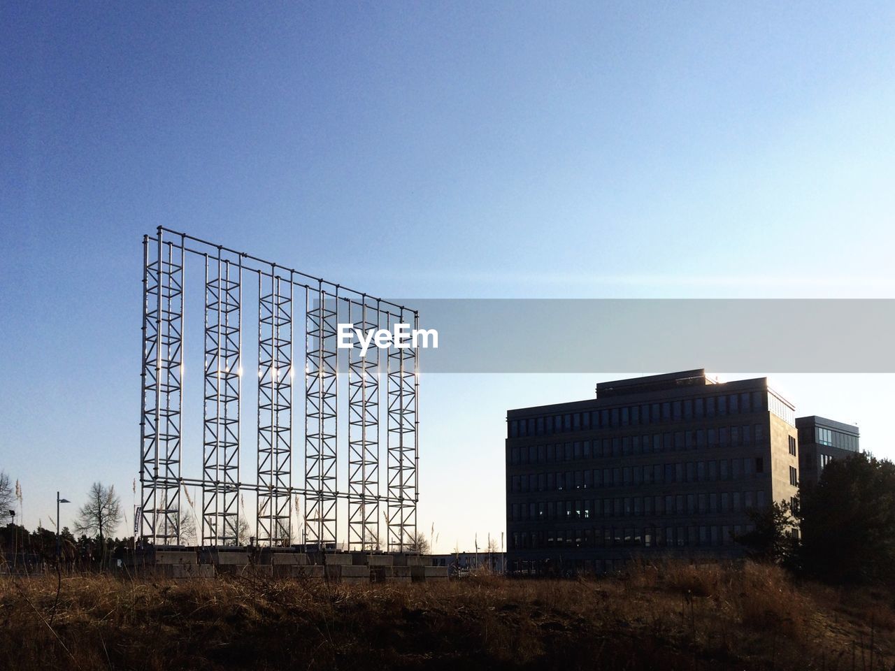 Low angle view of metallic structure and buildings against blue sky