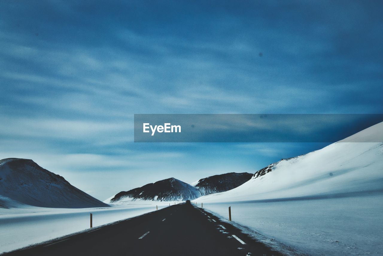 Road amidst snowcapped mountains against sky