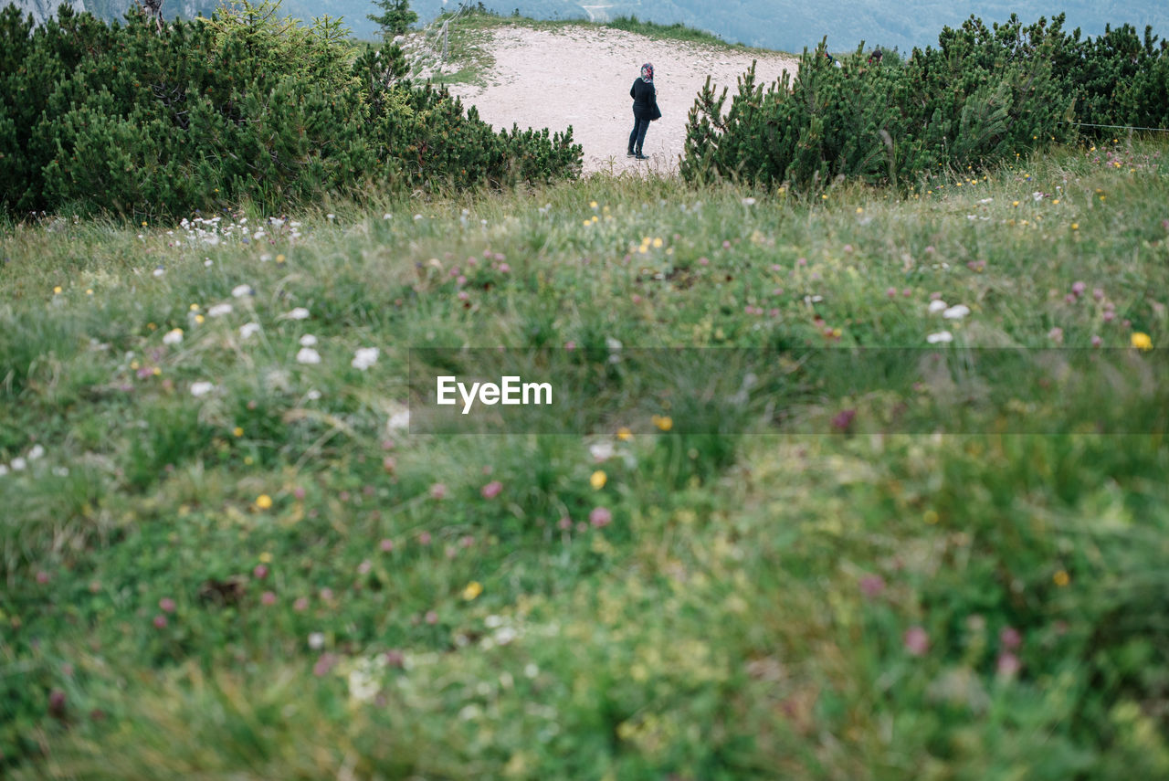 MAN STANDING ON GRASSY FIELD