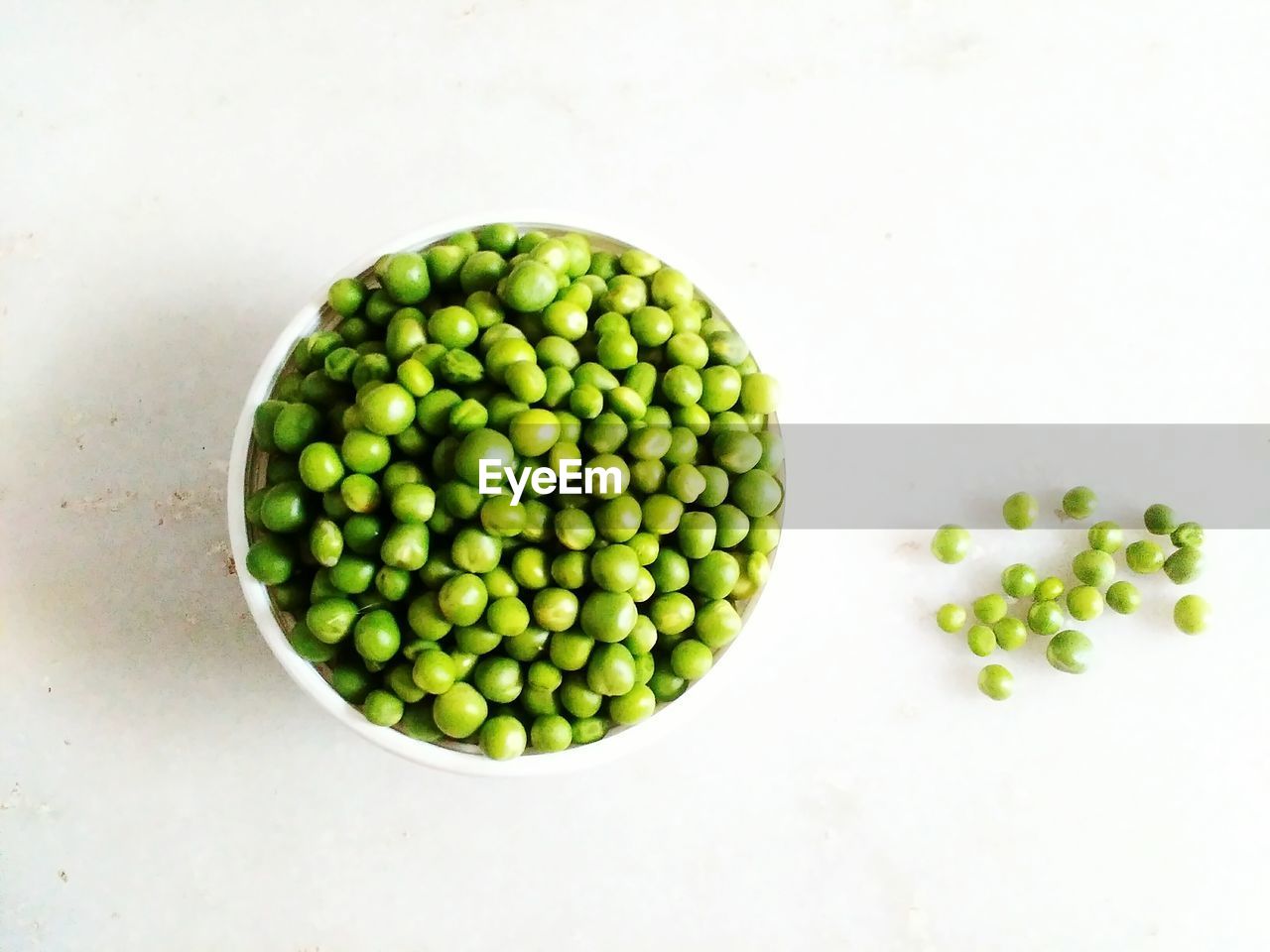 Directly above shot of green peas in bowl over white background