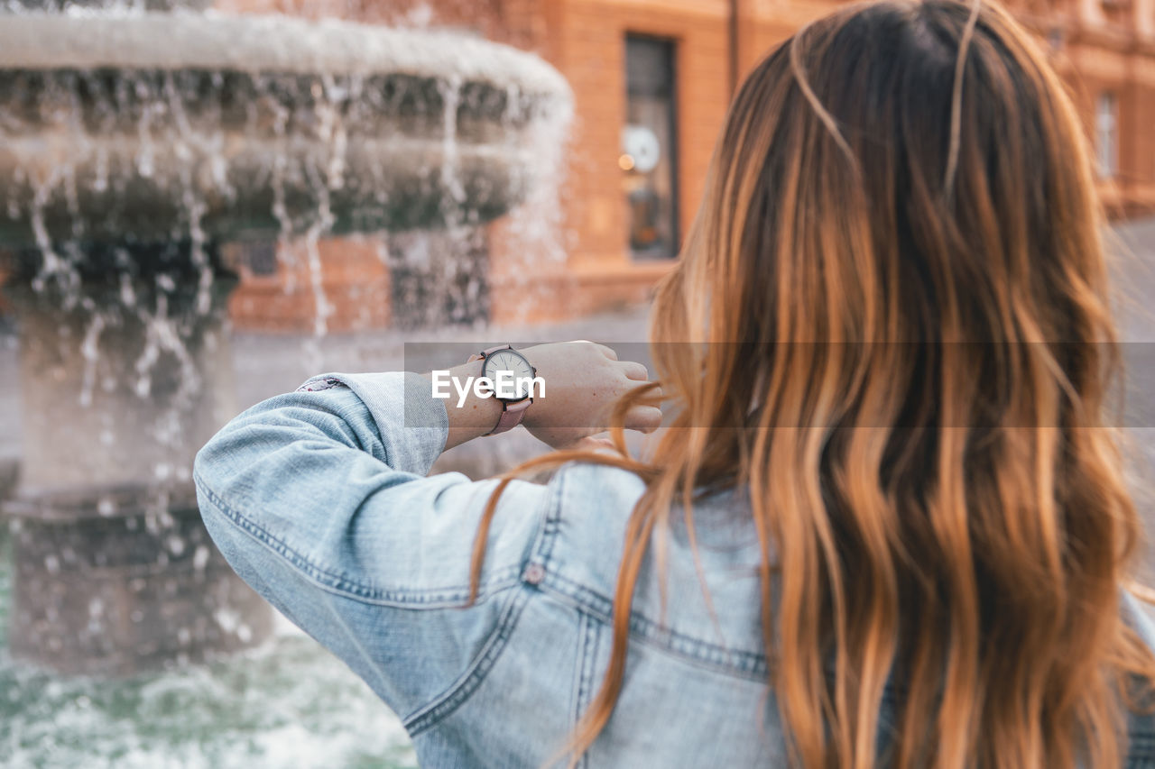 Close-up of woman checking time in city