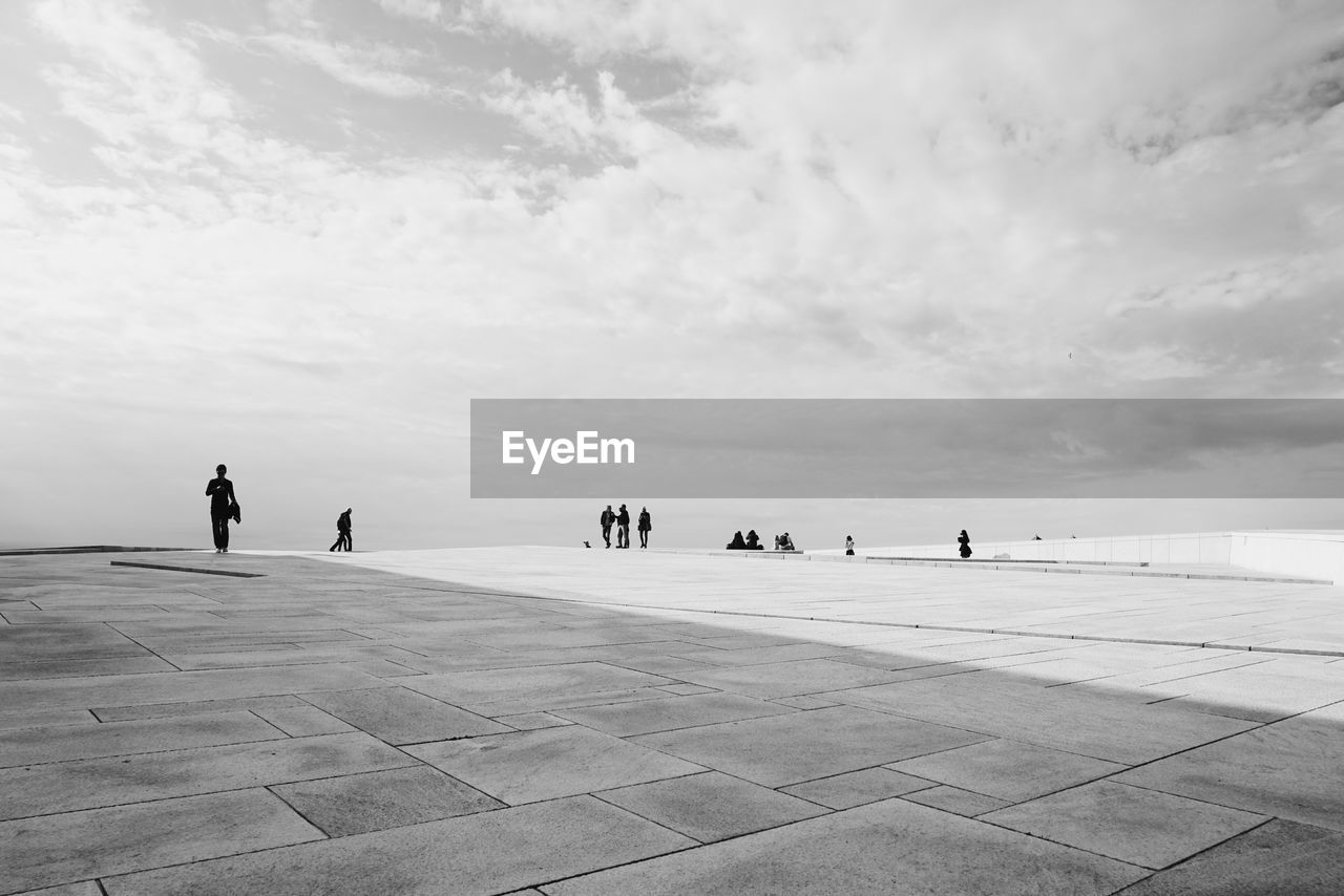 People at oslo opera house against cloudy sky