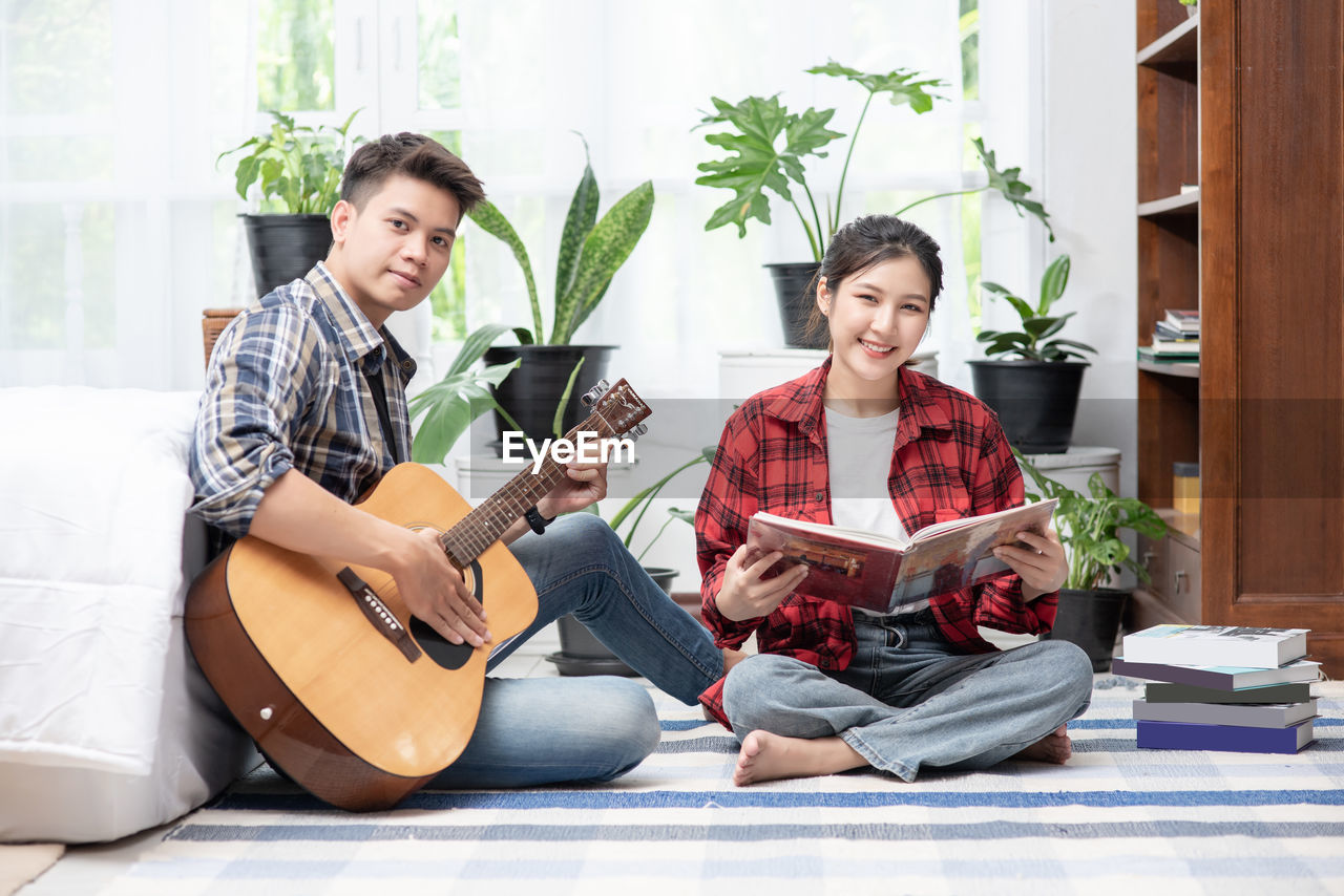 HAPPY YOUNG COUPLE SITTING ON GUITAR