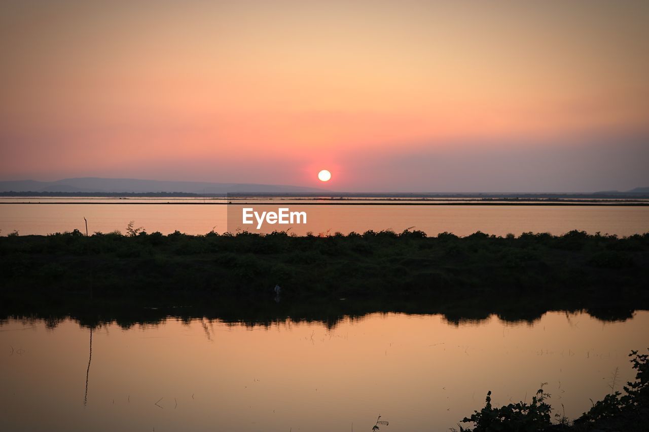 SCENIC VIEW OF LAKE AGAINST ORANGE SKY