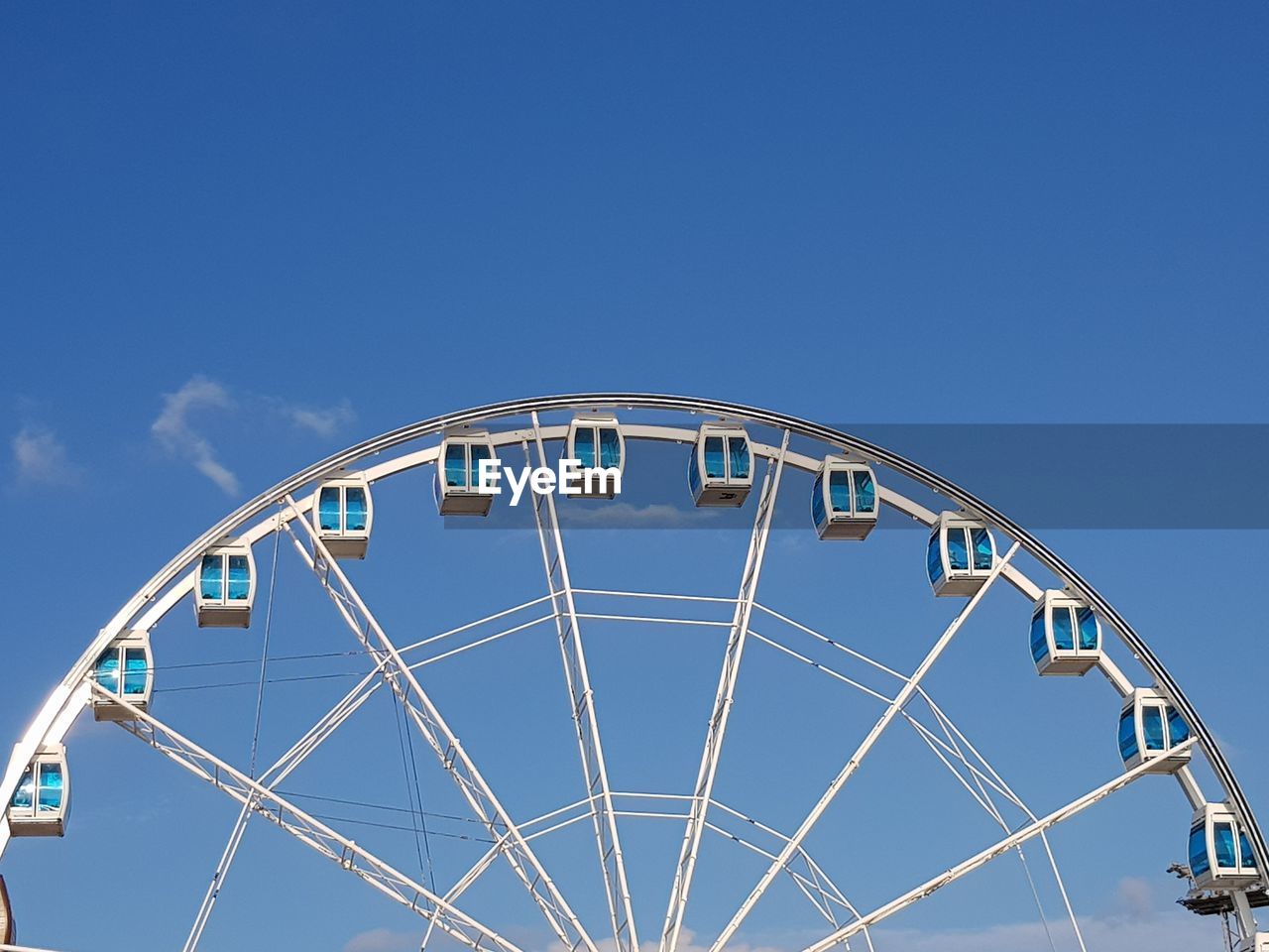 Low angle view of ferris wheel against blue sky