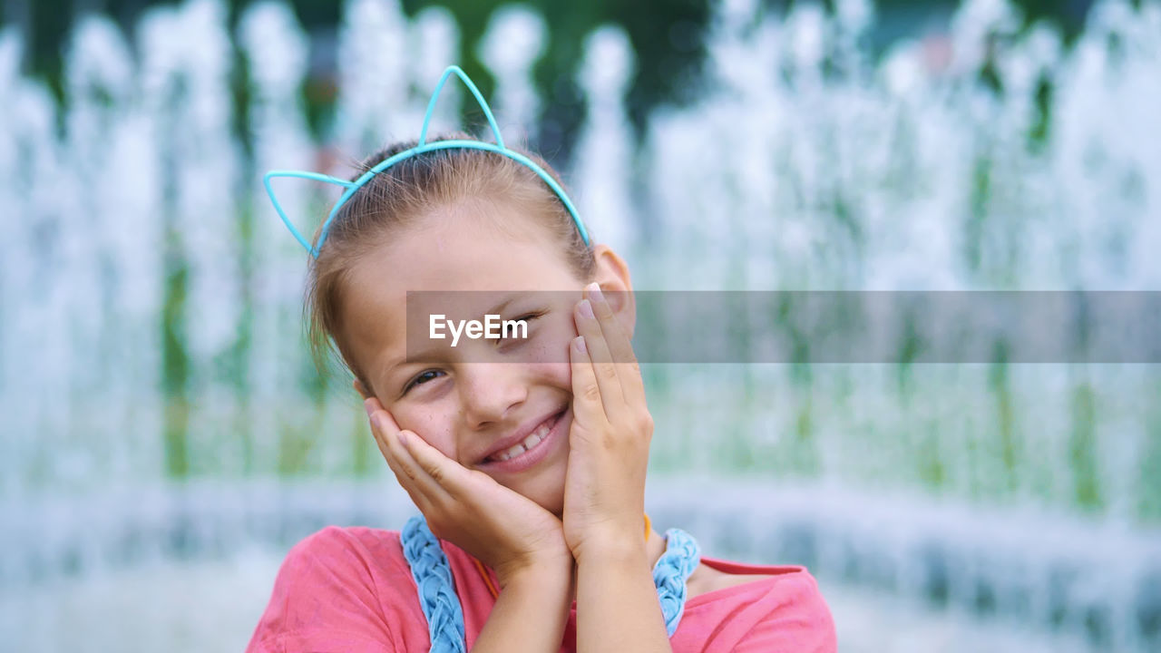 Portrait of a smiling, happy eight-year-old girl in a fun hoop with ears on her head, hair ornament.