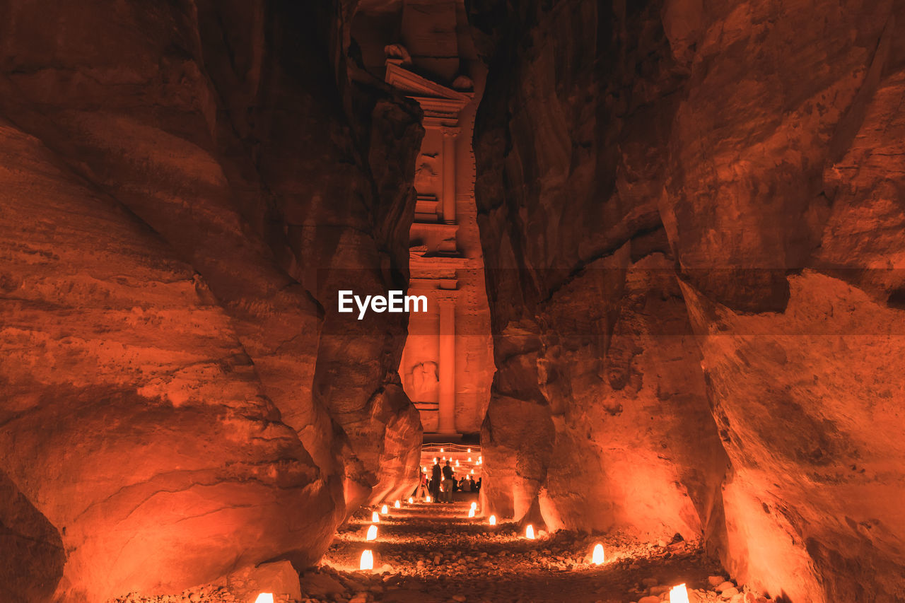 Illuminated walkway amidst rock formations at petra at night